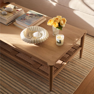 Neptune Frome Coffee Table in Solid Natural Oak with curved corners a woven undershelf and tapered legs set in a living room 